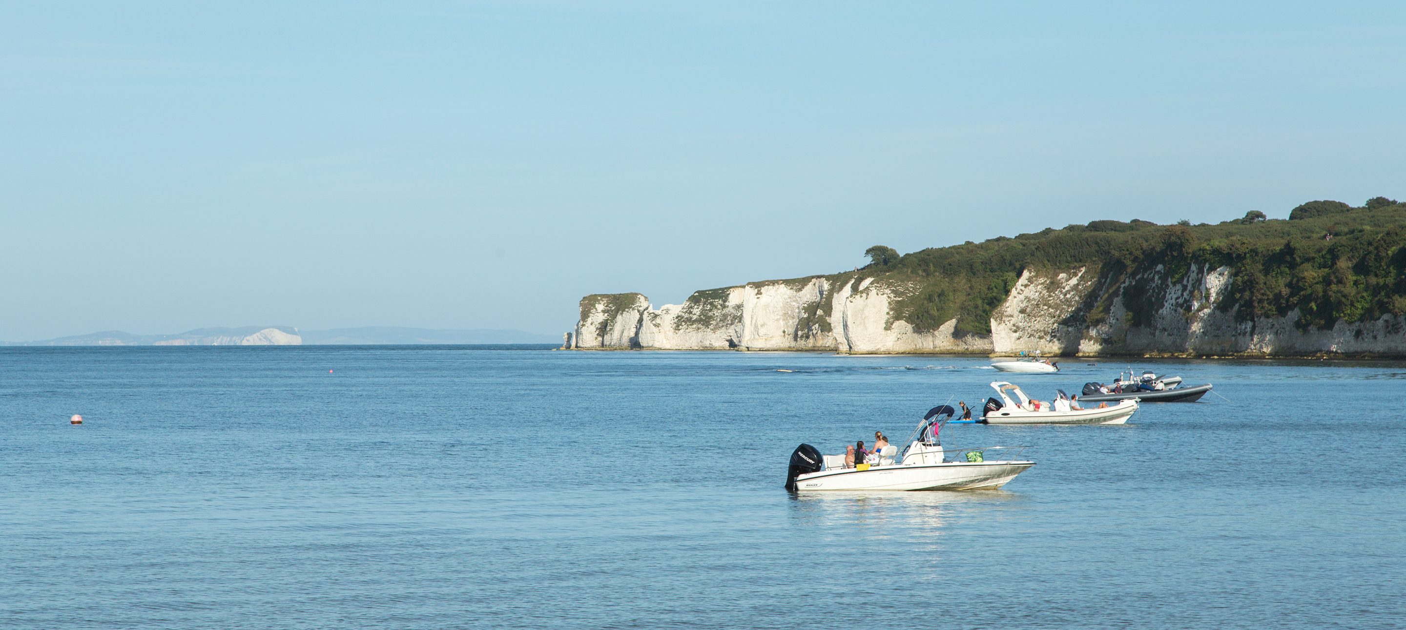 Studland Bay view with motor boats and white cliffs